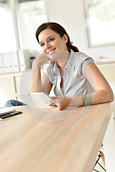 Smiling woman at work using tablet