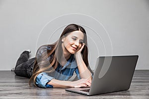 Smiling woman working on laptop on floor