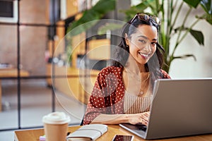 Smiling woman working on laptop and looking at camera