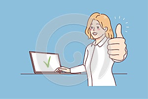 Smiling woman working on laptop showing thumb up