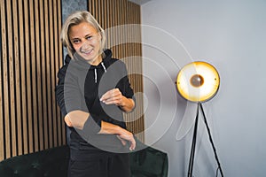 smiling woman wrapping an elbow support brace and looking at the camera, living room