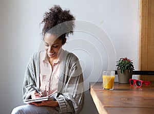 Smiling woman writing on note pad at home