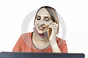 Smiling woman 40 years old wearing open protective face mask using laptop and cell phone during the end of coronavirus outbreak -