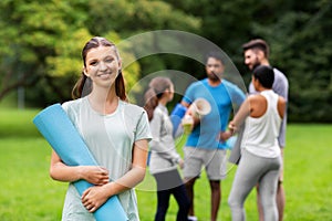 Smiling woman with yoga mat over group of people