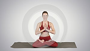 Smiling woman yoga meditating sitting lotus, hands coupled on gr