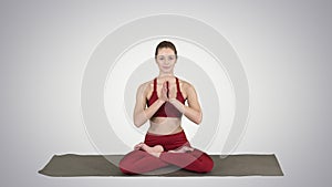 Smiling woman yoga meditating sitting lotus, hands coupled on gradient background.