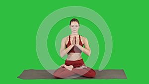 Smiling woman yoga meditating sitting lotus, hands coupled on a Green Screen, Chroma Key.