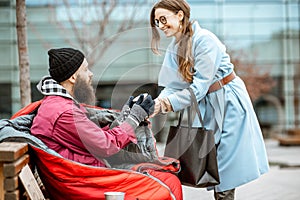 Woman giving a drink to a homeless beggar