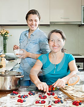 Smiling women making pies with berries