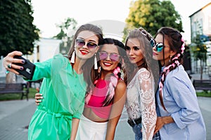 Smiling women posing and tacking self portrait at smart phones.