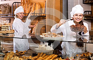 Smiling women selling fresh pastry and loaves