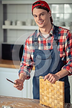 Smiling woodworker with a pair of carpentry tools at work