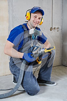 Smiling worker at concrete floor surface grinding by angle grinder machine