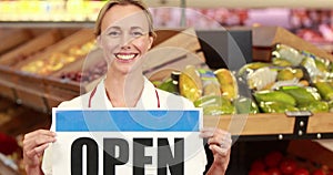 Smiling worker holding open sign
