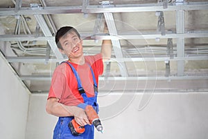 Smiling worker is installing a ceiling profile for