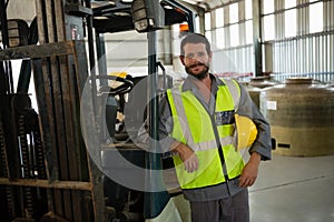 Smiling worker leaning on forklift in factory