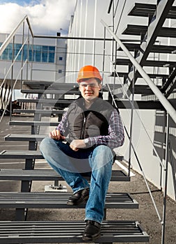 Smiling worker relaxing on metal staircase during break