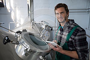 Smiling worker using digital tablet at factory