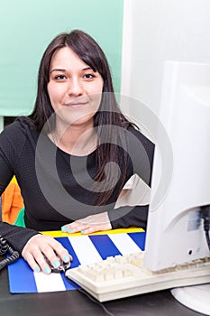 Smiling working woman behind computer monitor
