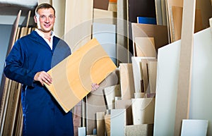 smiling workman standing with plywood pieces