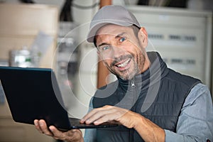 smiling workman using laptop he holding