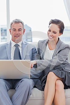 Smiling workmates working together sitting on sofa