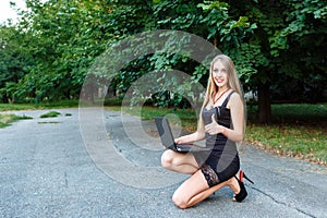 Smiling youg girl in black dress with laptop showing finger up.