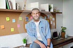 Smiling young adult bearded casual man looking at camera at home office.