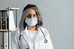 Smiling young adult indian female doctor wear white coat in medical clinic office. Happy beautiful health care india