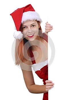 Smiling young adult woman in Christmas Santa hat holding plain white blank advertising board, copy space