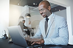 Smiling young African American businessman working on a laptop