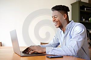 Smiling young african american businessman working on laptop at home