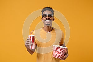 Smiling young african american guy in 3d imax glasses posing isolated on yellow orange background. People lifestyle
