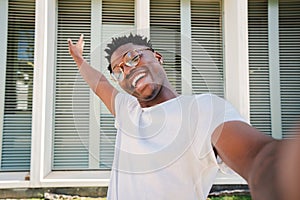 smiling young african american guy african american college student looking at camera and taking a selfie with his