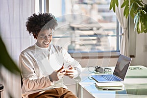 Smiling young African American guy using mobile phone at home.