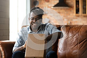 Smiling young african american man unpacking parcel.