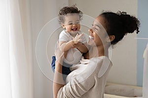 Smiling biracial mom play with little toddler infant