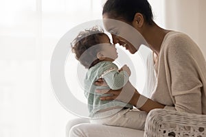 Smiling young african american mommy touching noses with cute kid.