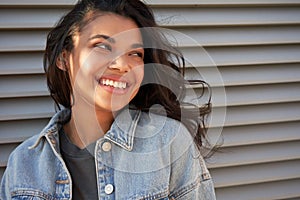 Smiling young African American teen girl looking away laughing, headshot.