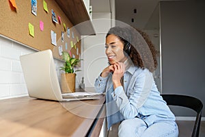 Smiling young african american teen girl wear headphone video calling on laptop.