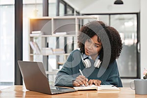 Smiling young african american teen girl wear headphones video calling on laptop. Happy woman student looking at