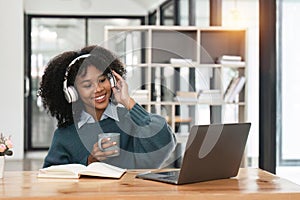 Smiling young african american teen girl wear headphones video calling on laptop. Happy woman student looking at
