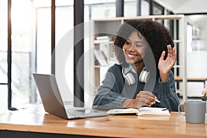 Smiling young african american teen girl wear headphones video calling on laptop. Happy woman student looking at