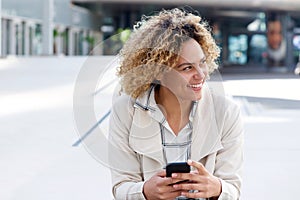 Smiling young african american woman with cellphone outside