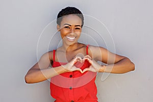 Smiling young african american woman with heart shape hand sign