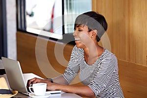 Smiling young african american woman using laptop