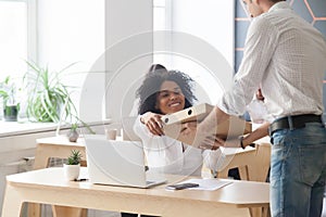 Smiling african employee taking pizza from courier, office food