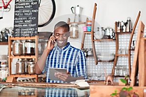 Smiling young African entrepreneur busy working in his cafe