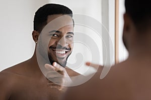 Smiling young african ethnicity man pointing finger looking at camera.