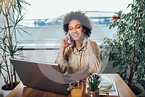 Young African female entrepreneur sitting at a desk in her home office working online with a laptop